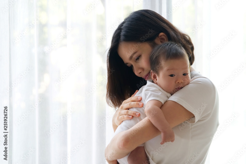 Close up portrait view of beautiful Asian mother holding her newborn baby in her arms and support ba