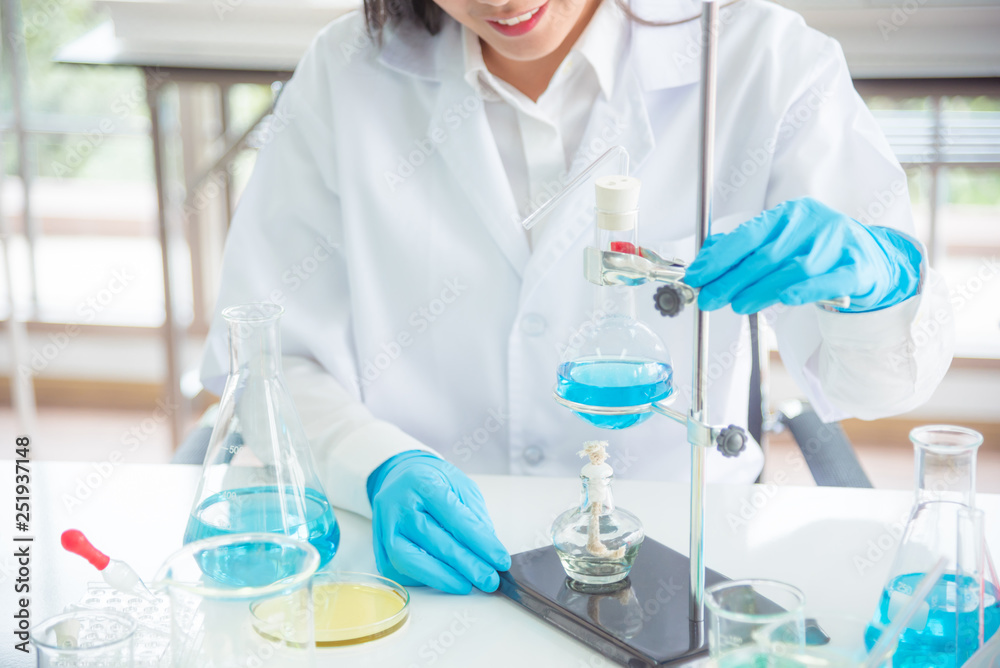 Scientist doing experiment in lab,many glassware on table.