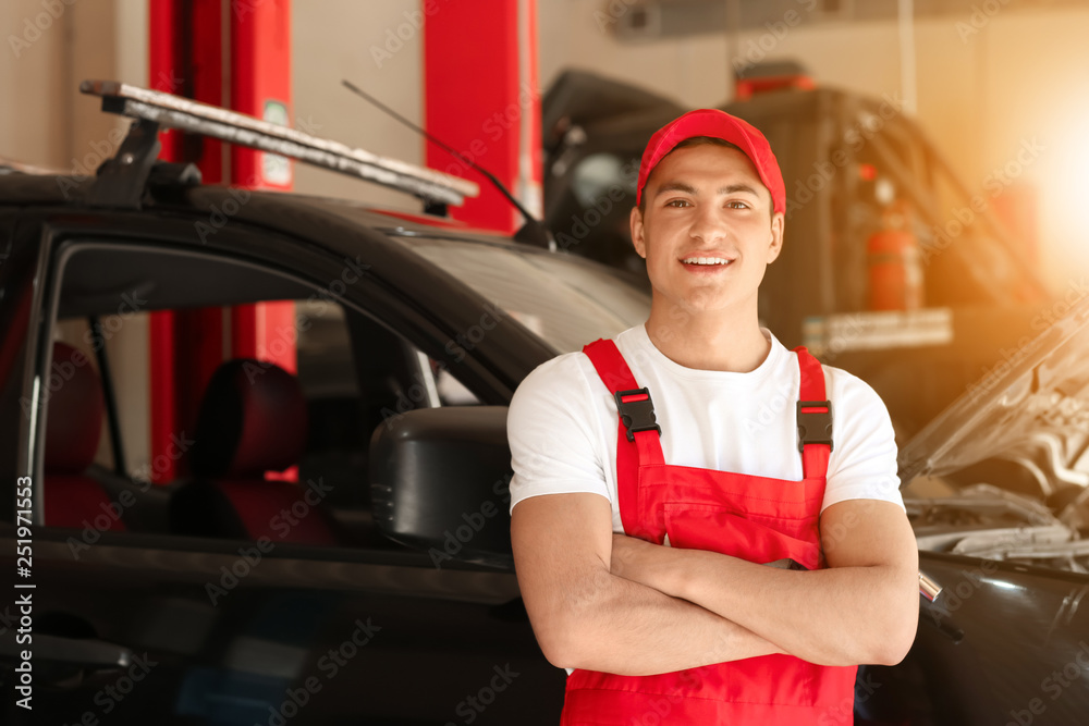 Young auto mechanic near car in service center