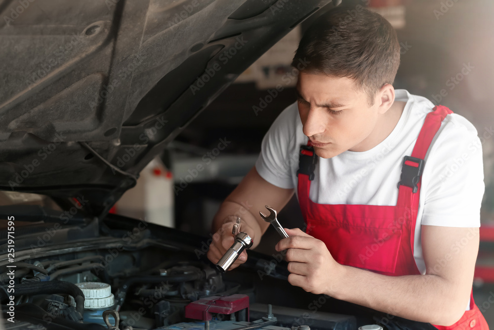 Young auto mechanic repairing car in service center