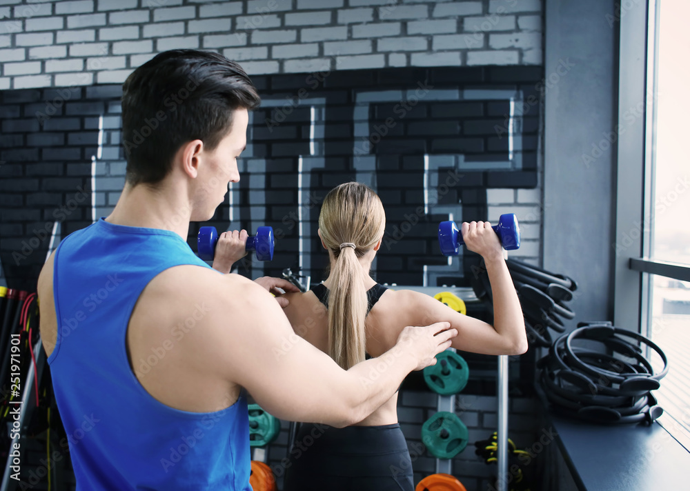 Young woman training with coach in modern gym