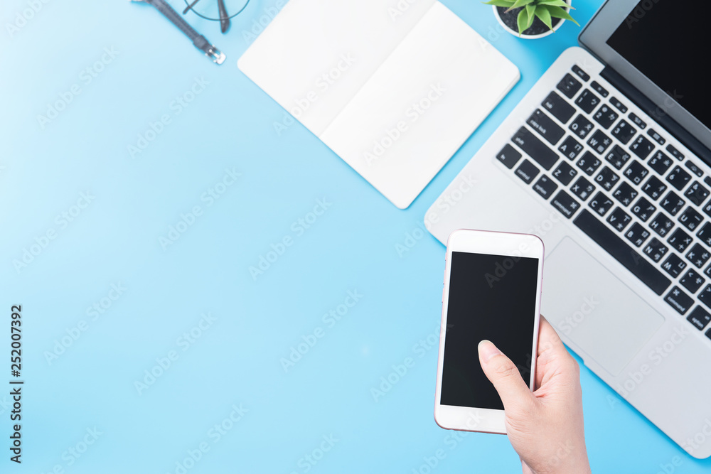 A woman is holding a smartphone isolated with a minimal blue desk, concept of online shopping paymen