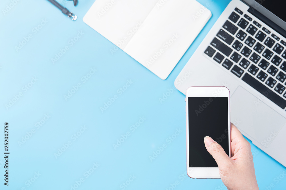 A woman is holding a smartphone isolated with a minimal blue desk, concept of online shopping paymen