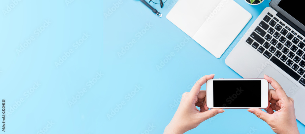 A woman is holding a smartphone isolated with a minimal blue desk, concept of online shopping paymen