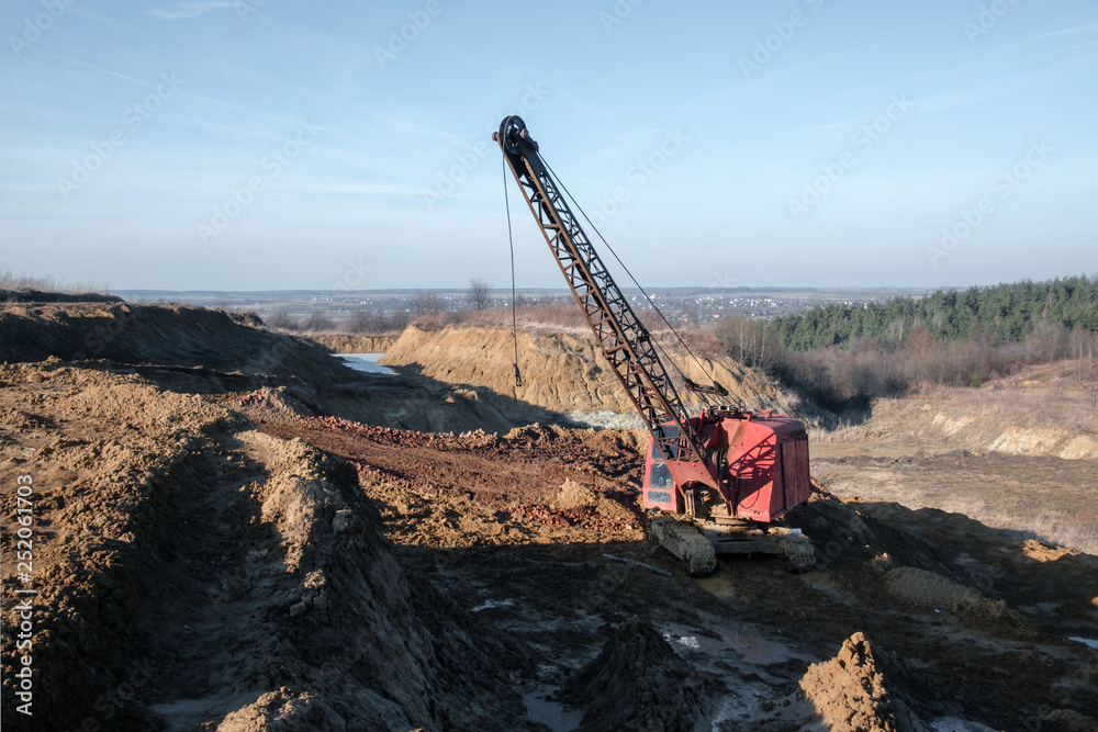 Excavator in the red clay quarry. Industrial background