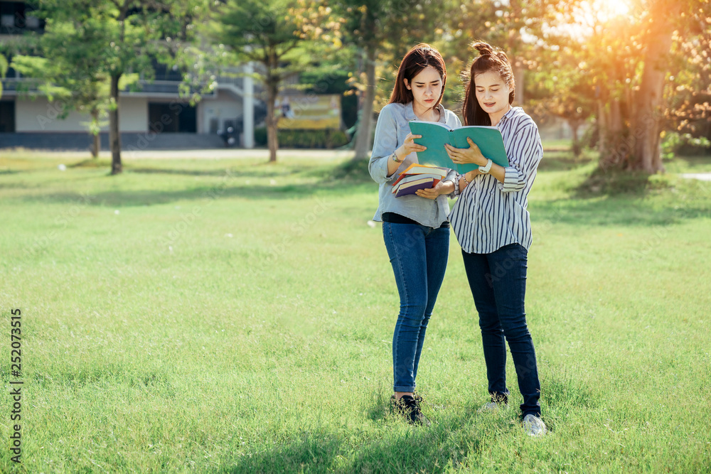 A group of teenage student in university smiling and reading the book in summer holiday.