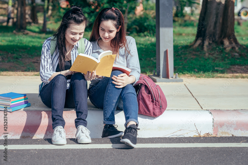 A group of teenage student in university smiling and reading the book in summer holiday.