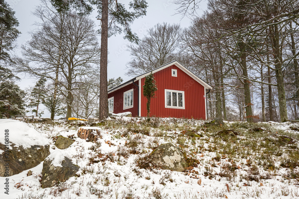 Snowy winter scenery with red wooden house in the forest, Sweden