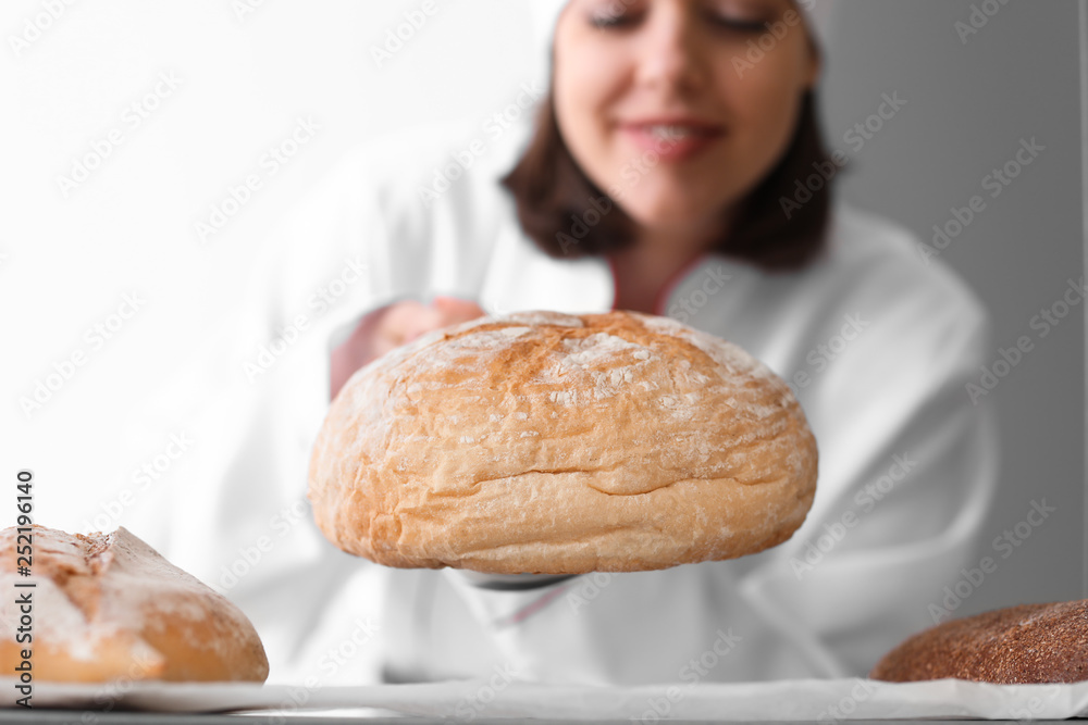 Female chef with freshly baked bread in kitchen