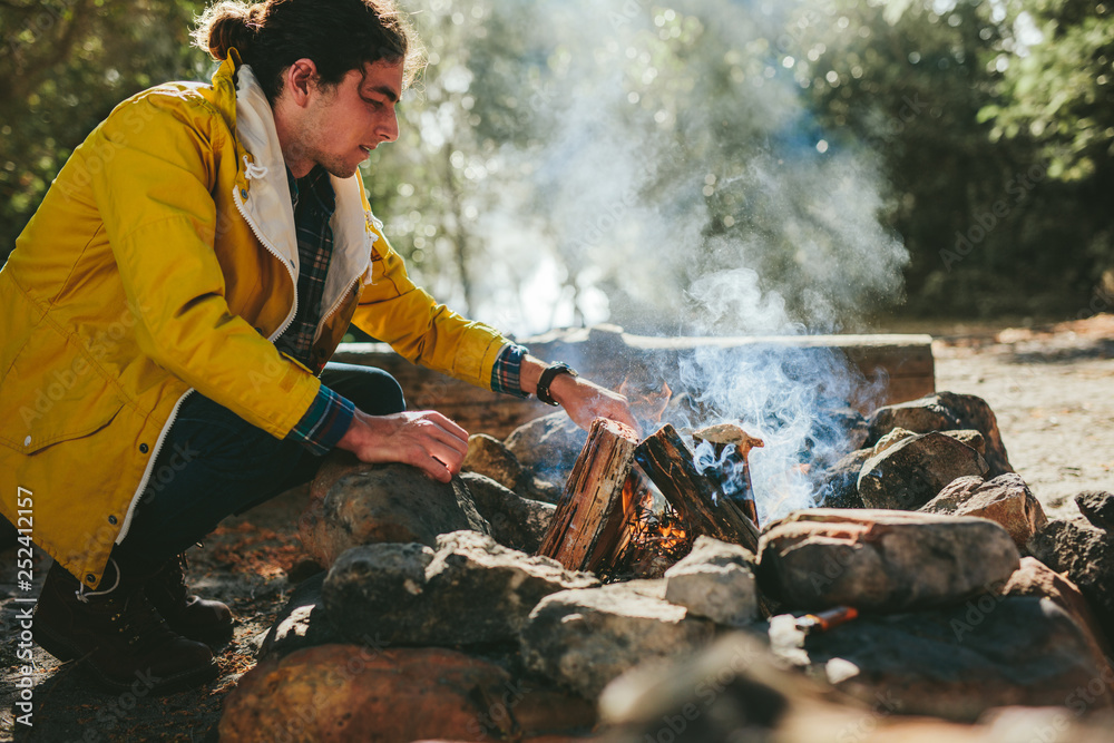 Man setting up a campfire in  a forest