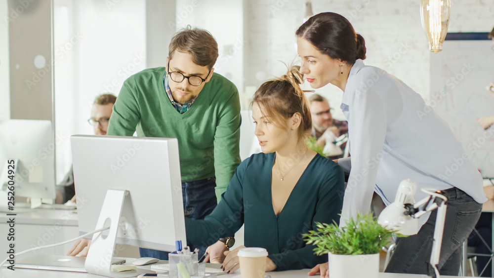 In Brightly Lit and Modern Creative Bureau. In Foreground Three Creative People Discuss Business Iss