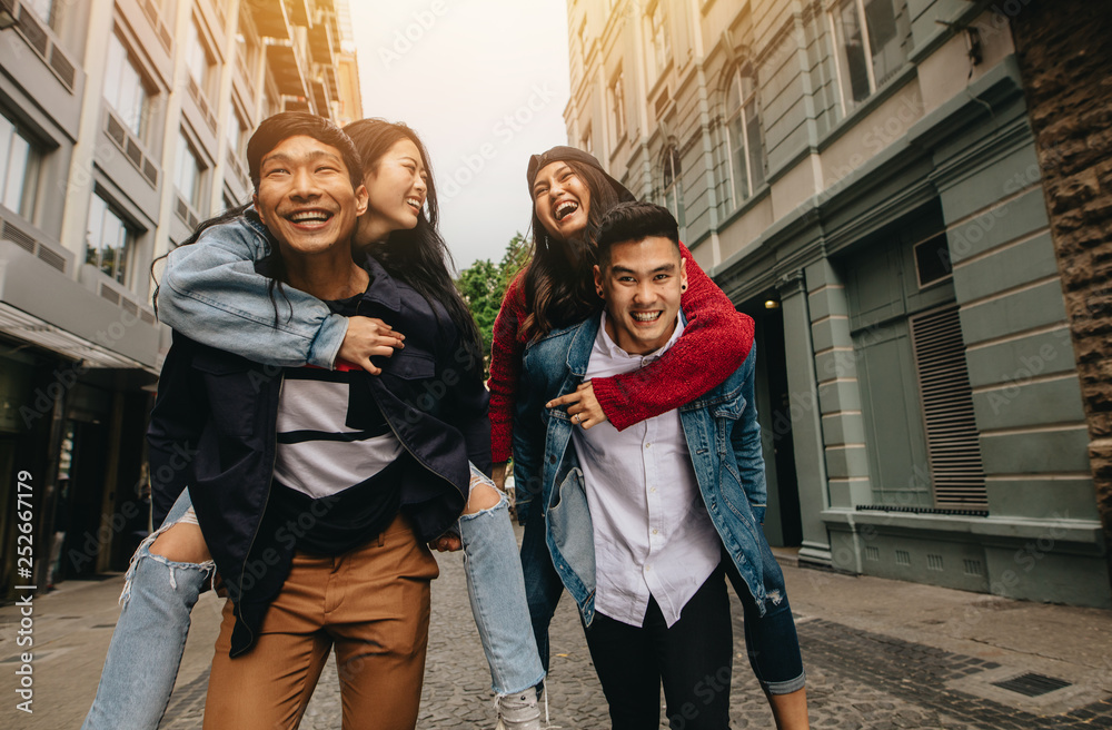 Friends piggybacking outdoors on city street