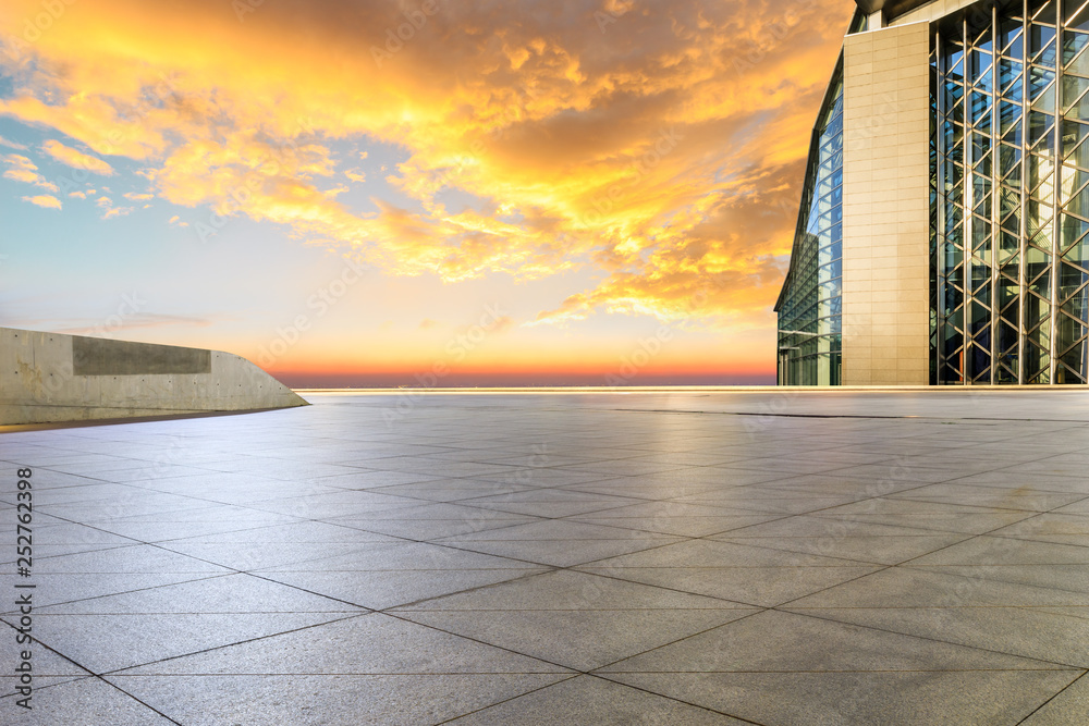 Empty square floor and modern city skyline with buildings at sunset