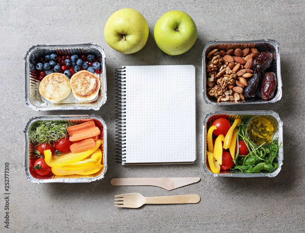 Containers with delicious food and blank notebook on grey background