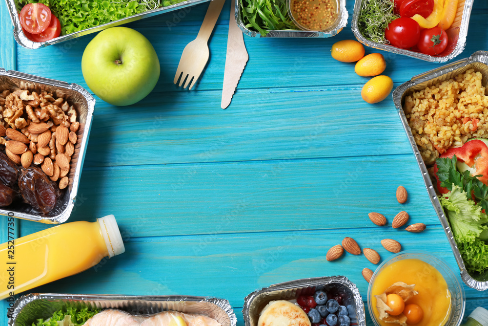 Frame made of containers with delicious food on wooden background