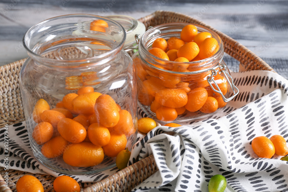 Jars with delicious kumquat fruit on table