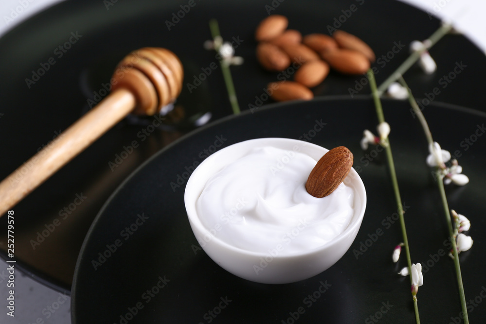 Bowl with natural cream on plate, closeup