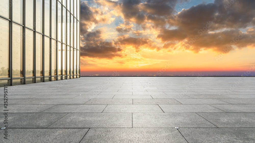 Empty square floor and modern city skyline with buildings at sunset