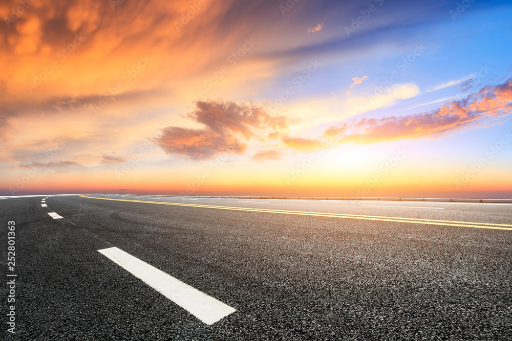 Empty asphalt road and beautiful colorful clouds at sunset