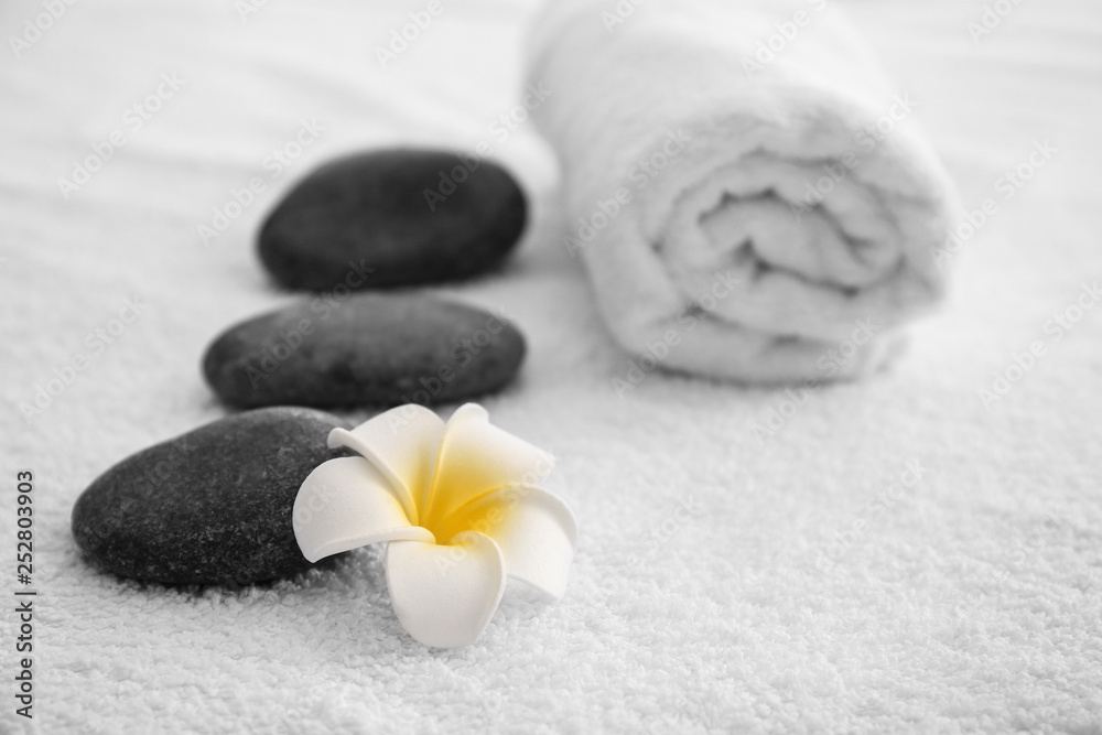 Massage stones, towel and flower on table in spa salon