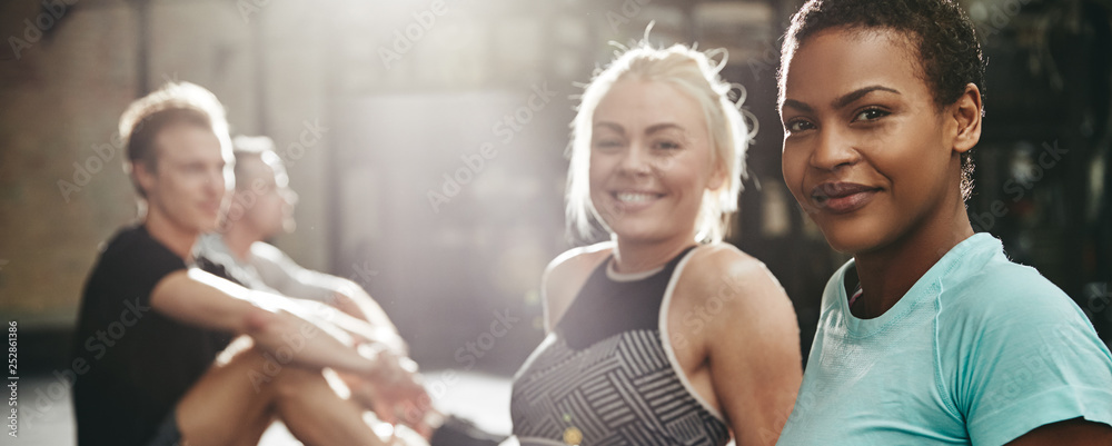 Smiling women sitting on a gym floor after working out