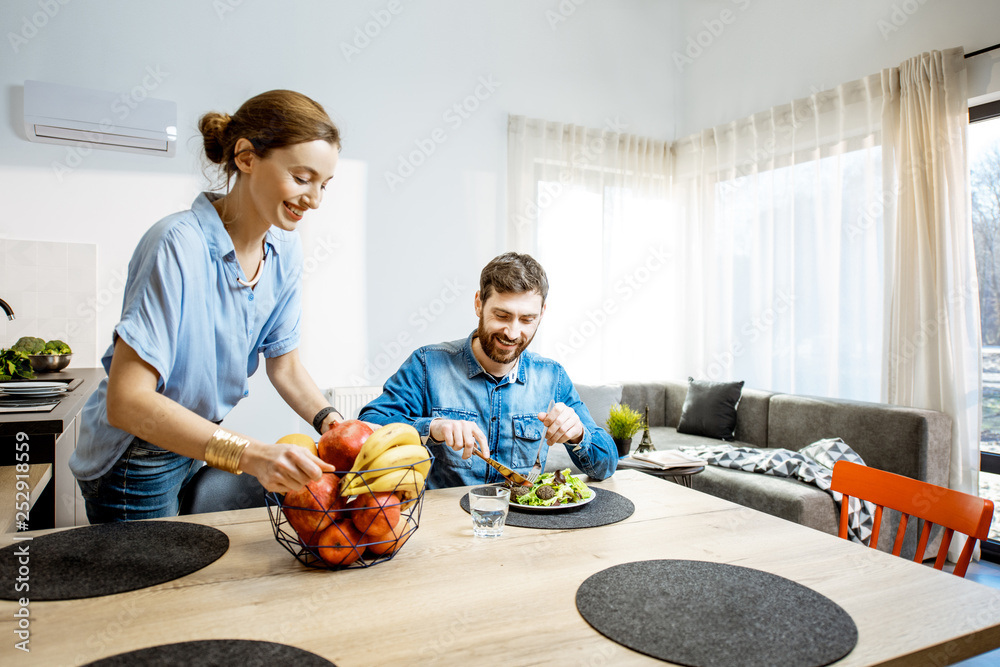 在现代人的客厅里享用健康食品，晚餐时间快乐的男人和女人