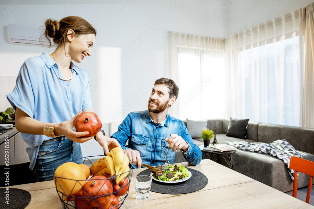 在现代人的客厅里享用健康食品，晚餐时间快乐的男人和女人