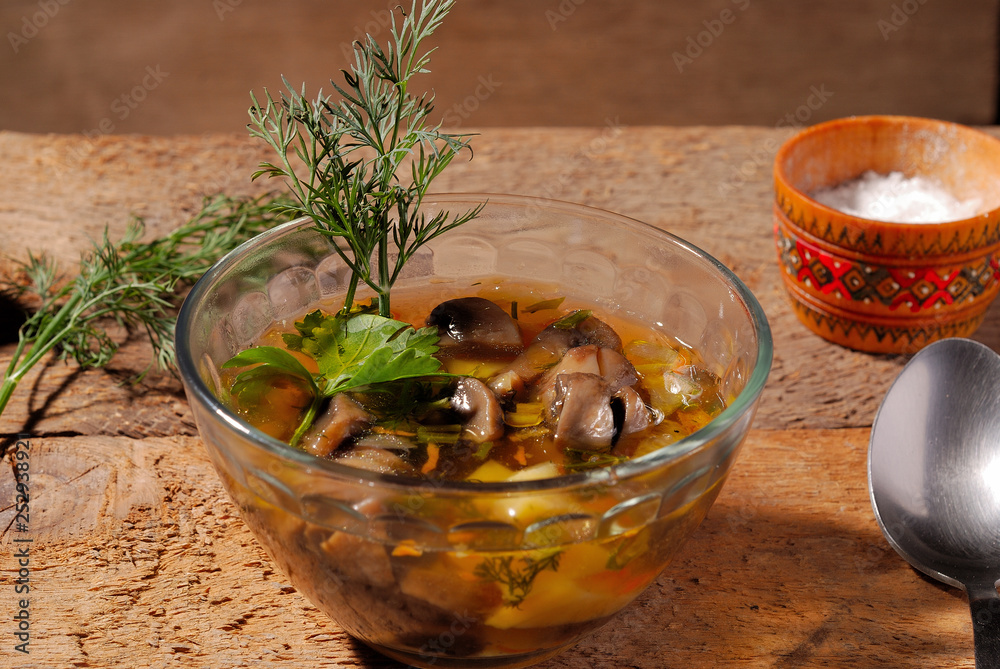 Mushroom soup with dill, on wooden background in a glass bowl