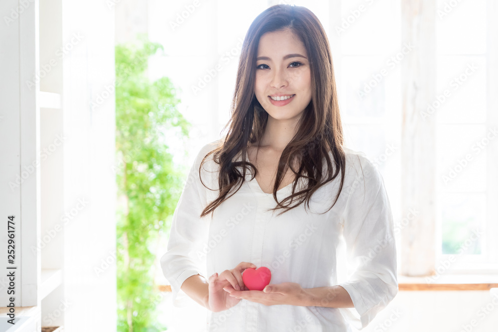 attractive asian woman holding heart symbol