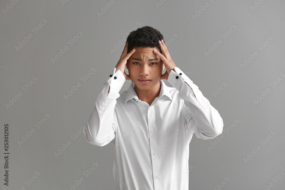 Sad African-American boy after failing school test on grey background