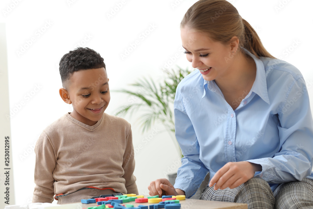 Little boy with speech therapist composing words of letters in office