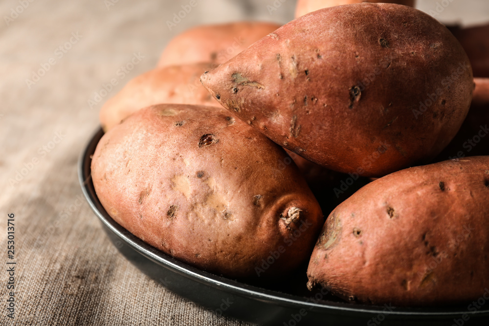 Plate with raw sweet potato on table, closeup