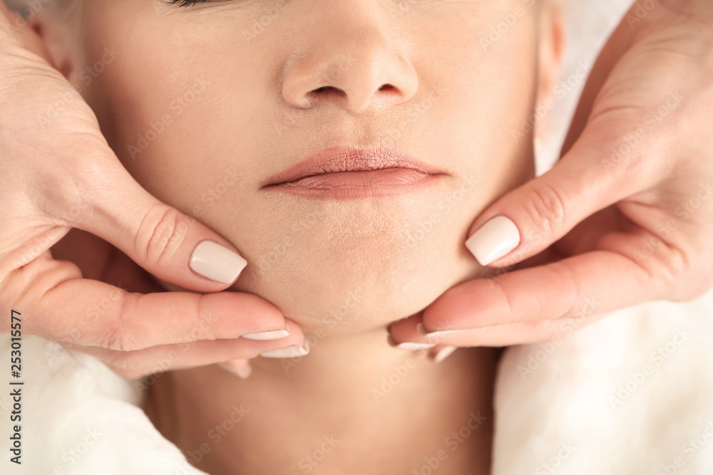 Mature woman receiving face massage in beauty salon, closeup