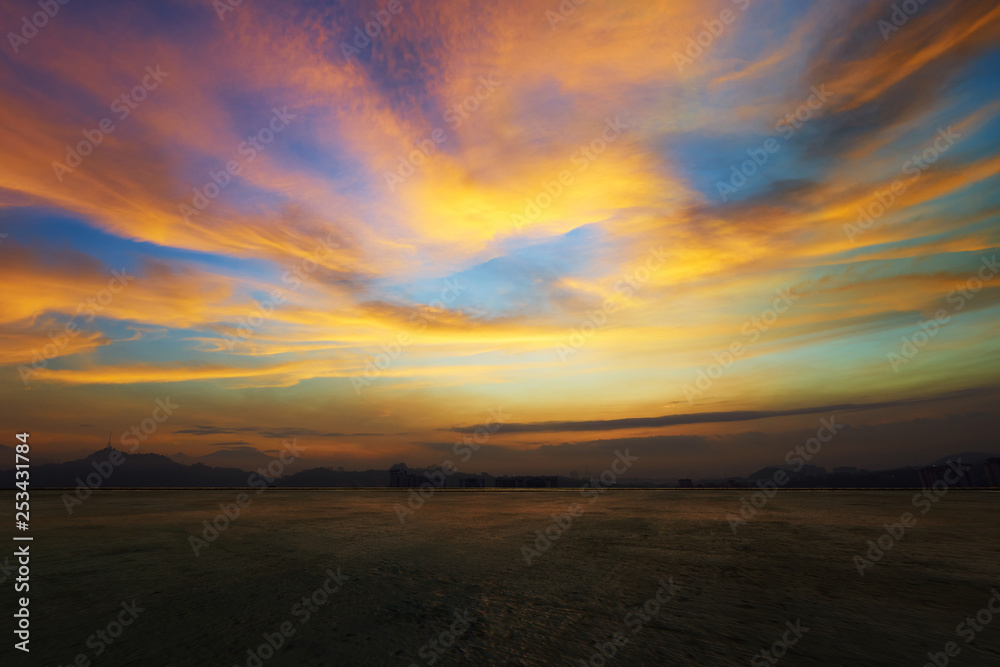 Empty concrete cement floor with dramatic evening orange and yellow sky .