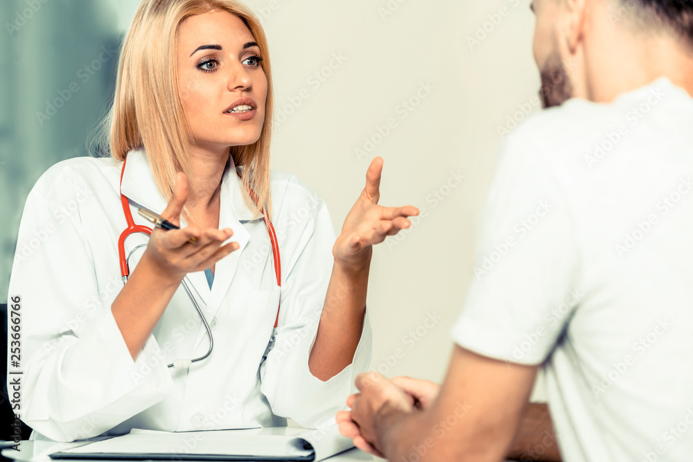 Woman doctor is talking to male patient in hospital office. Healthcare and medical service.