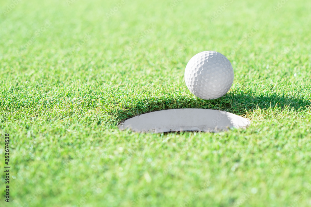 Golf ball and golf hole on green grass with copy space