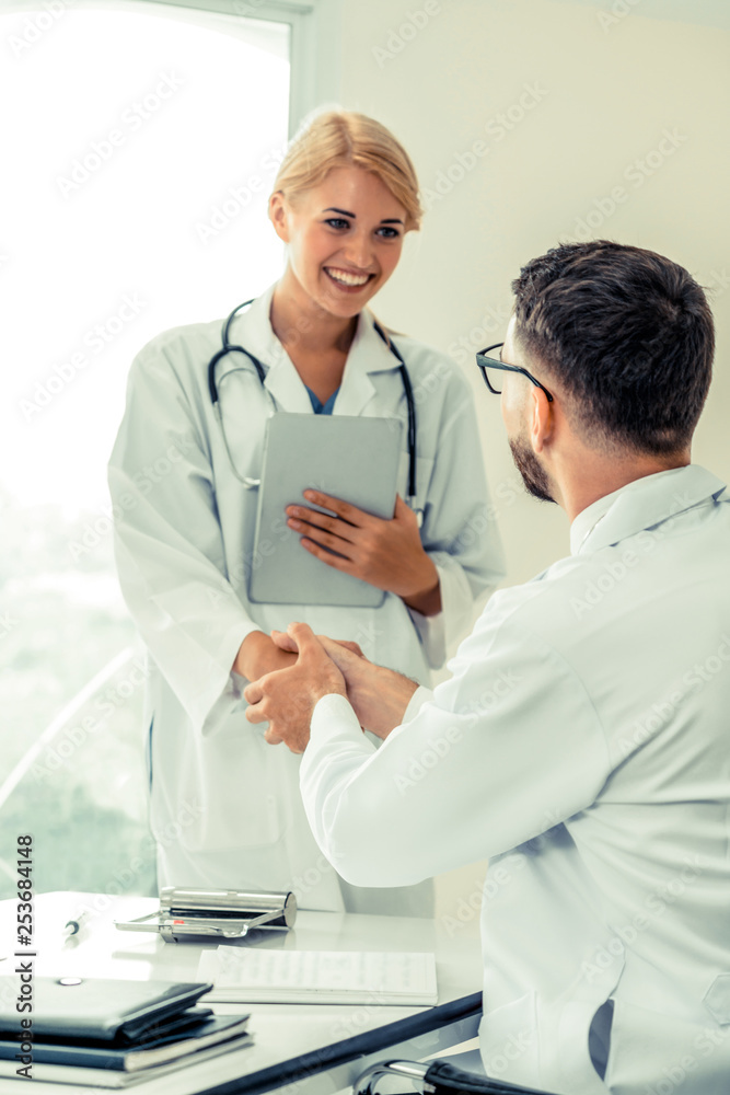 Doctor at the hospital giving handshake to another doctor showing success and teamwork of profession