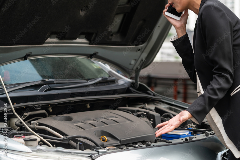 Young businesswoman whose car breakdown uses mobile phone to call for roadside assistance service. T