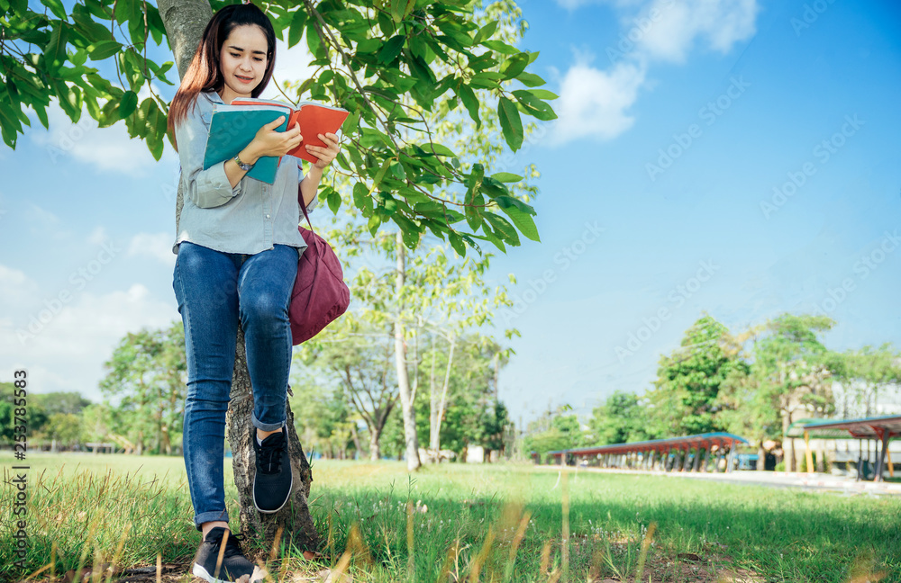 A group of teenage student in university smiling and reading the book in summer holiday.