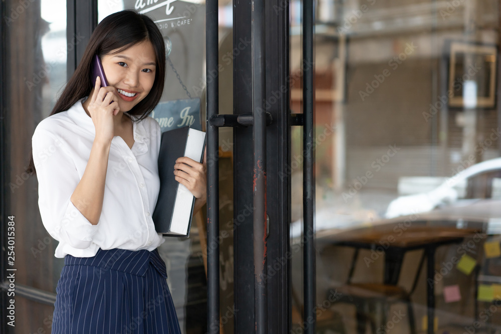 Portrait of Asian girl enter door to coffee shop .Businesswoman using phone and walking to cafe