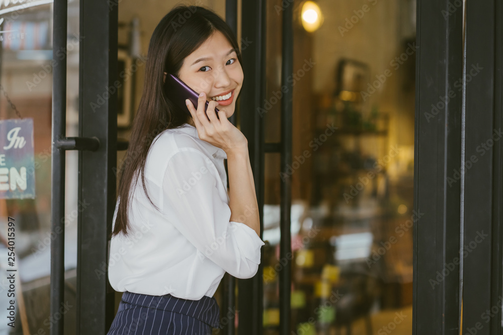 亚洲女孩的画像走进咖啡店的门。女商人打电话走向咖啡馆