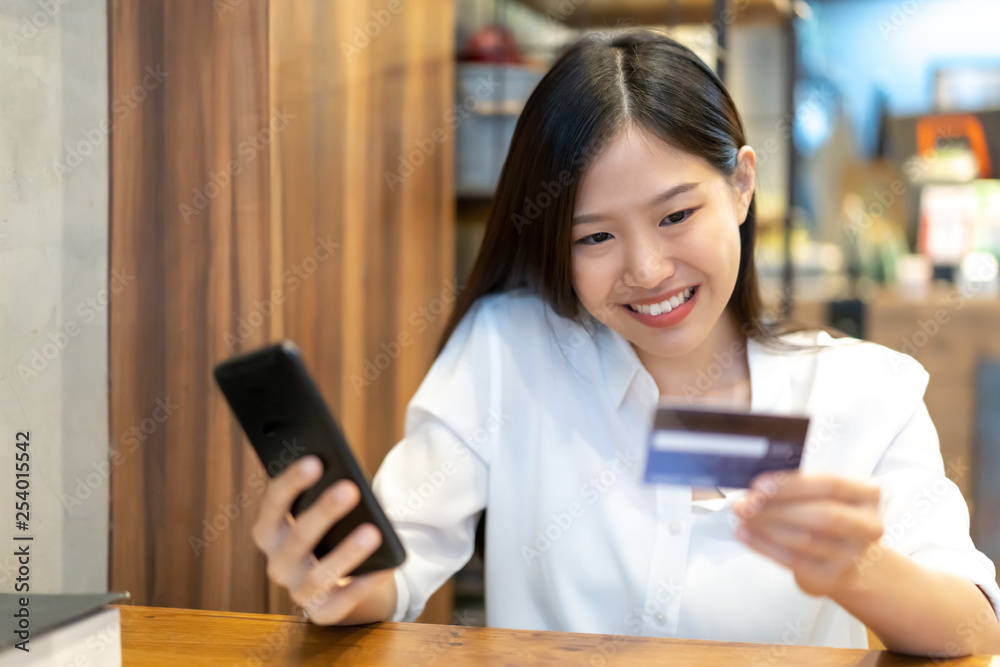 Young Asian woman using smartphone and credit card. Shopping buying online