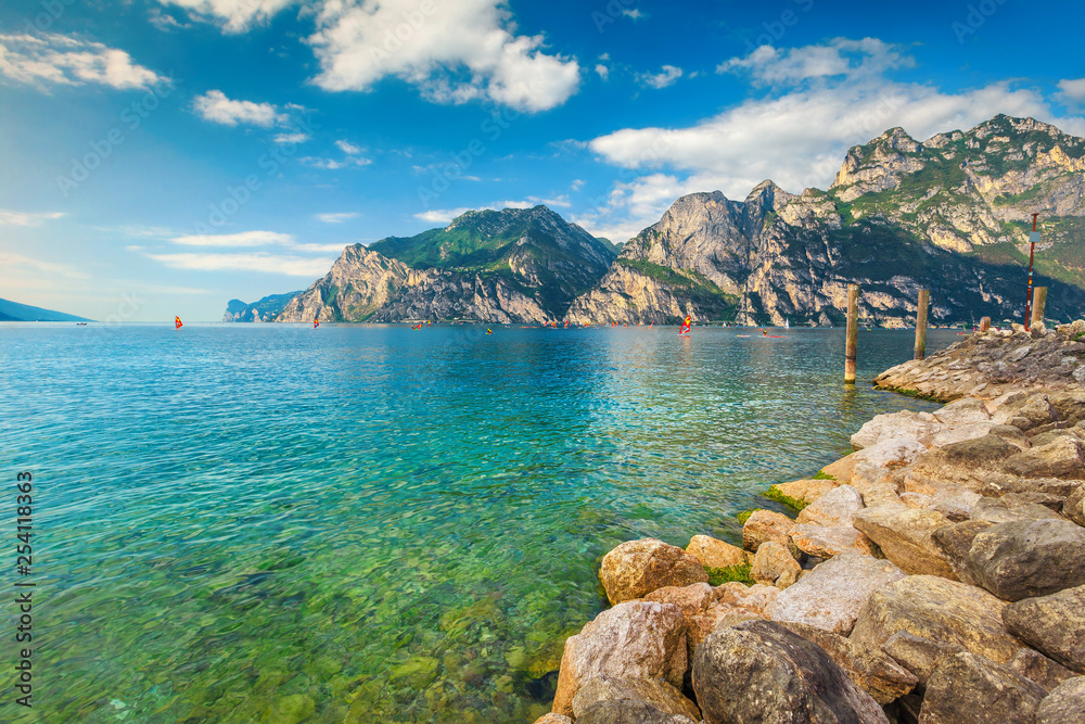 Lake Garda with surfers and high mountains in background, Italy