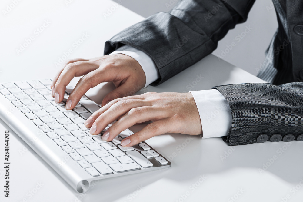 Closeup of businesswoman hand typing on keyboard with mouse on wood table