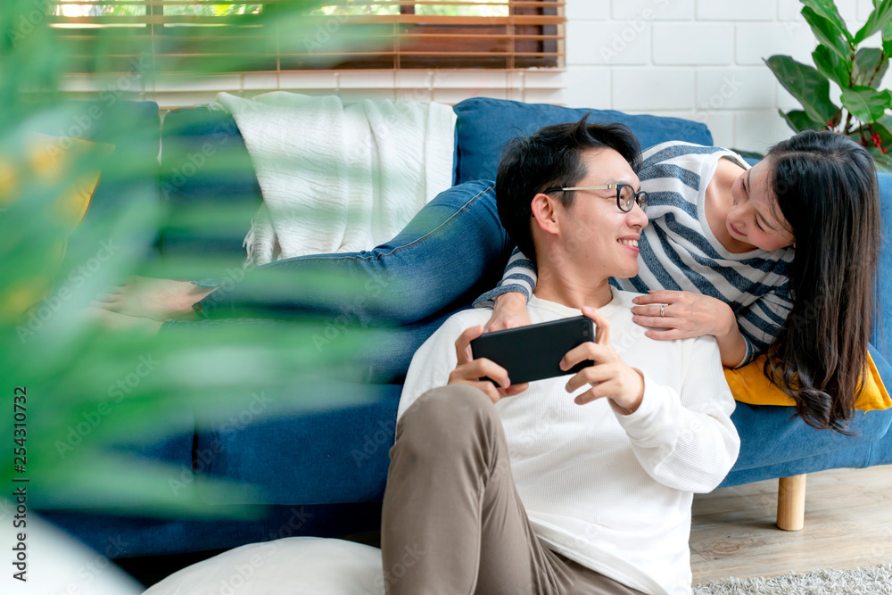 happiness asian sweet couple enjoy game on smartphone together living room home background