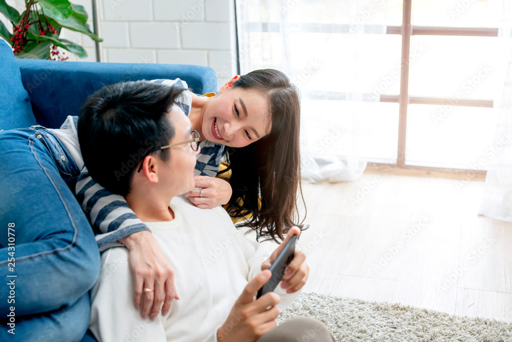 happiness asian sweet couple enjoy game on smartphone together living room home background