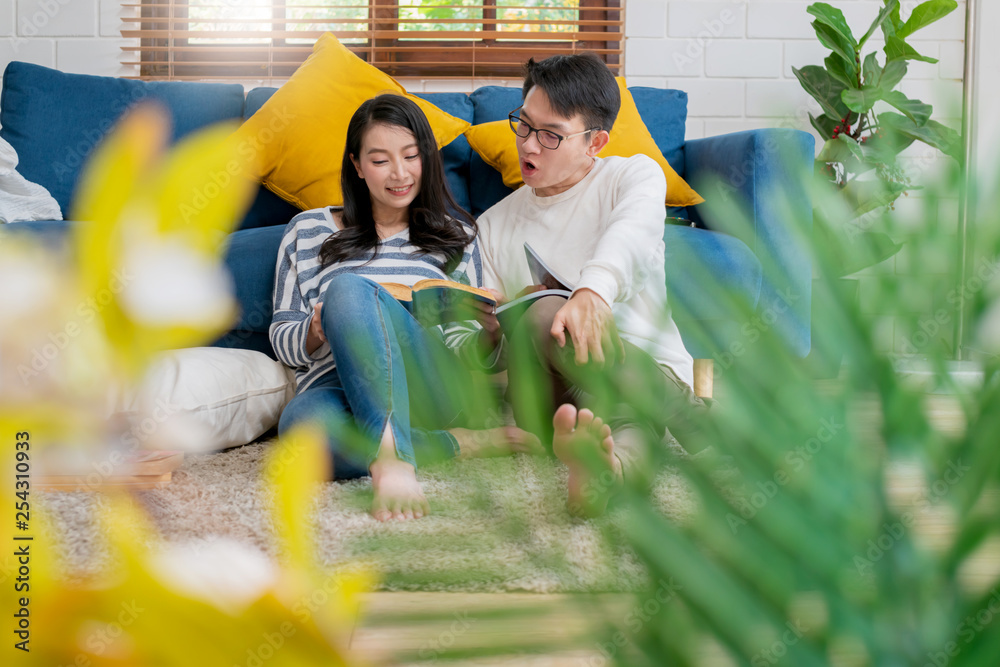 sweet lovey asian family couple sit talk good conversation and read book together next to sofa in li