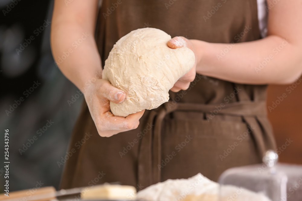 Female baker making dough in kitchen, closeup