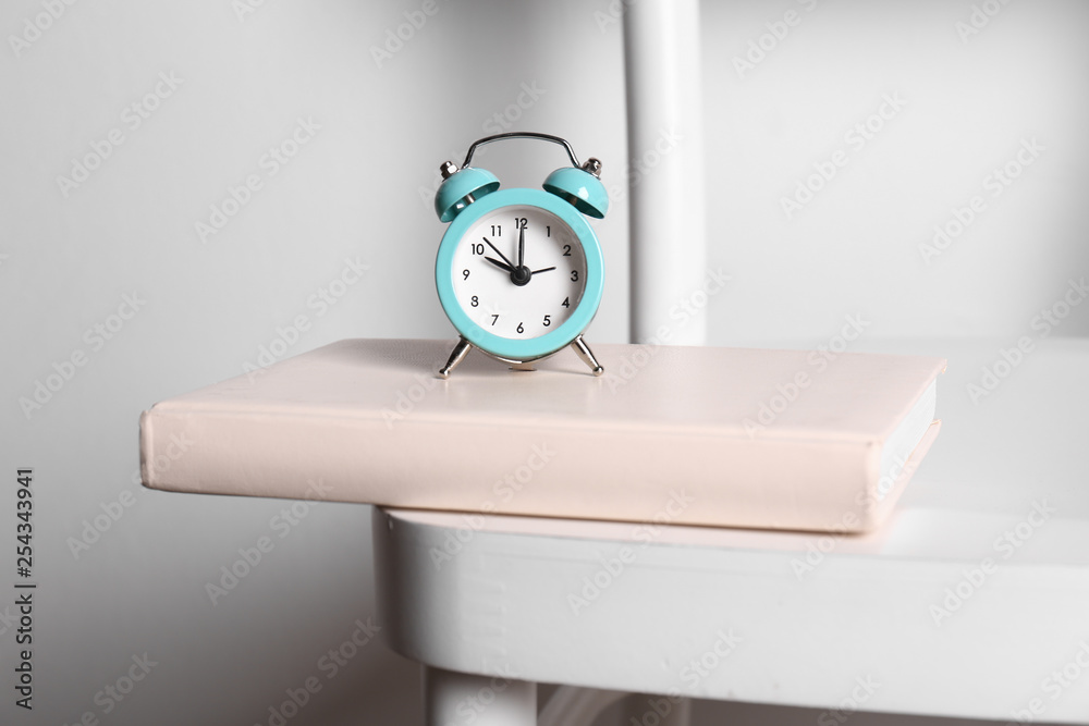 Alarm clock and book chair against white background