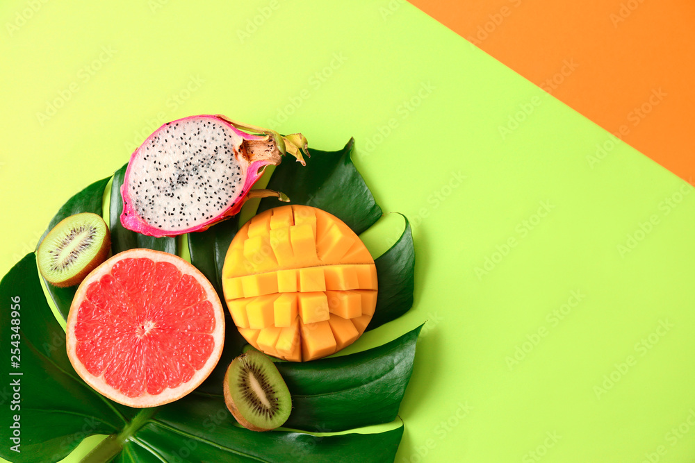 Assortment of exotic fruits with tropical leaf on color background